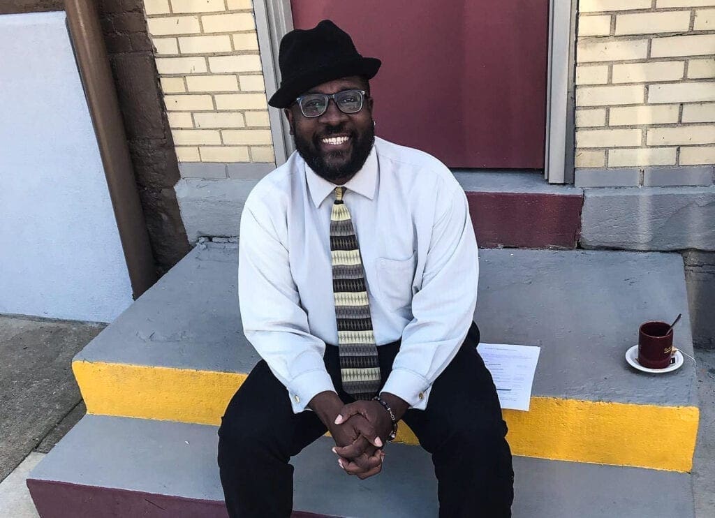 A black man sitting on a step.