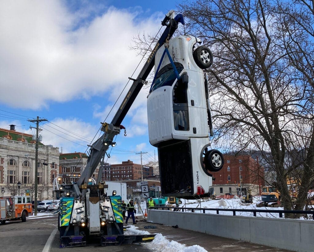 A white truck dangling from a tow truck.