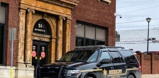 A photo of a black truck in front of a building.