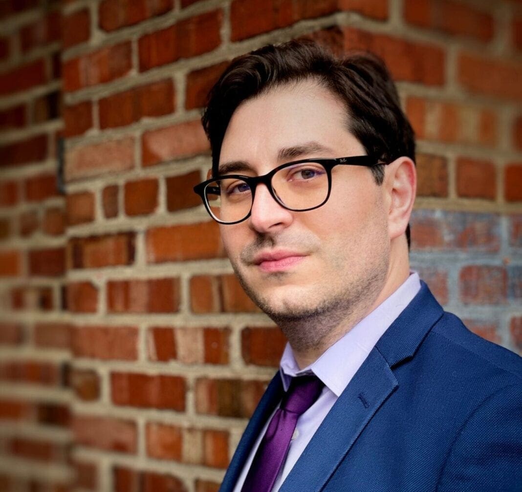 A man wearing a tie and dark glasses.