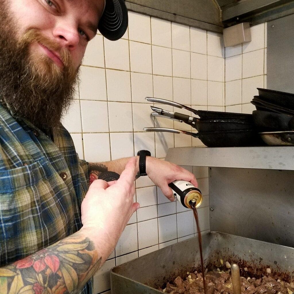 A man pouring beer in a soup.