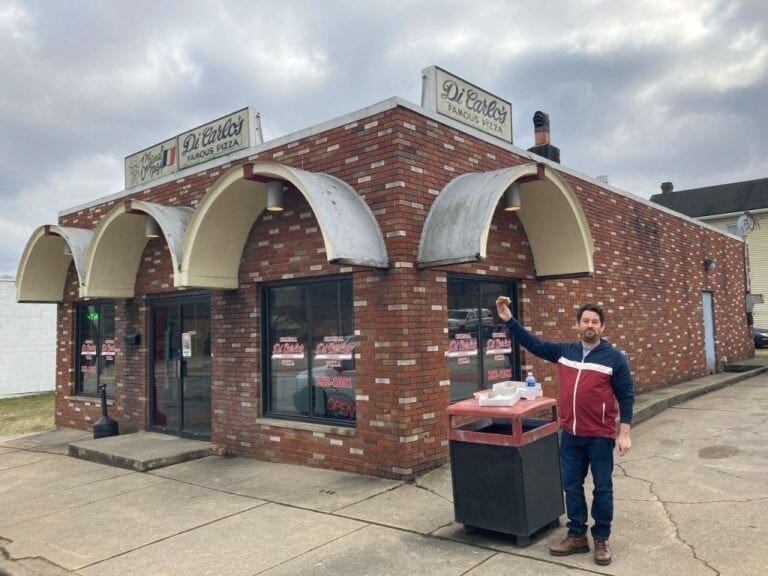 A man outside of a pizza shop.