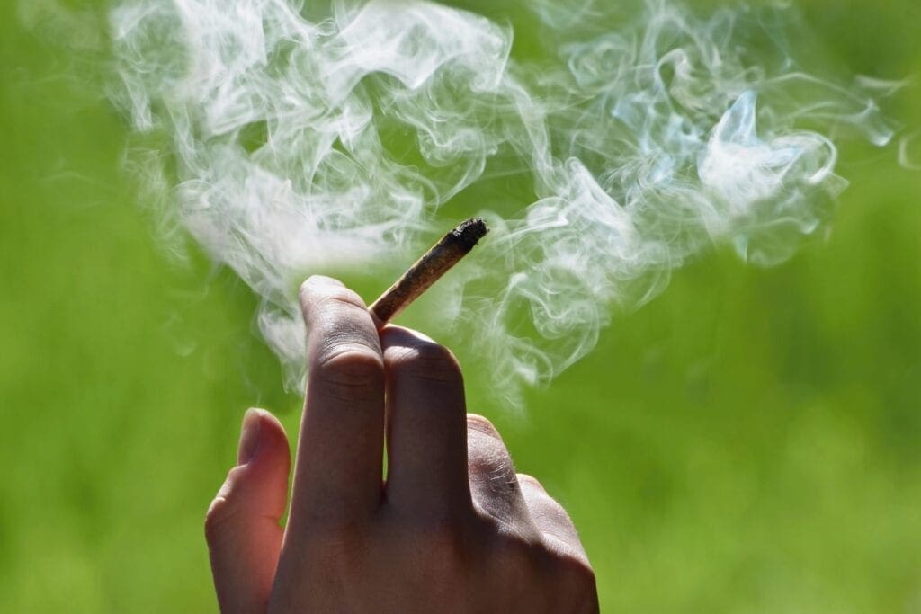 A human hand holding a marijuana cigarette.