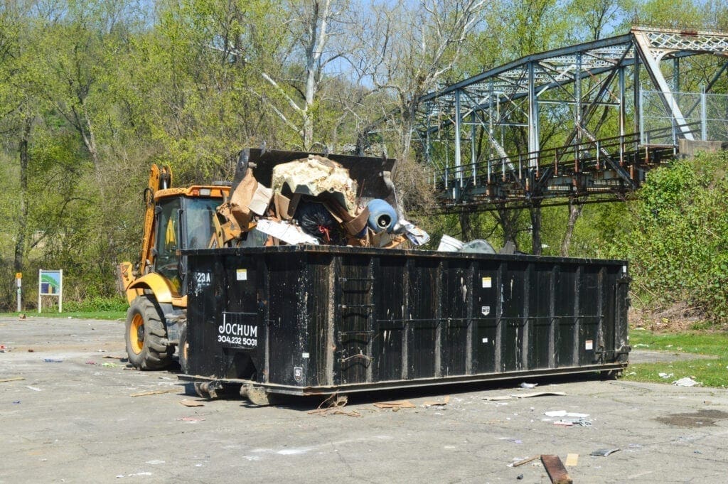 A backhoe filling a dumpster.