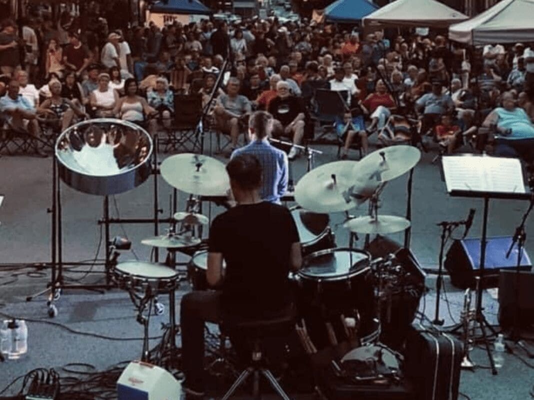 A man playing the drums in front of a lot of people.