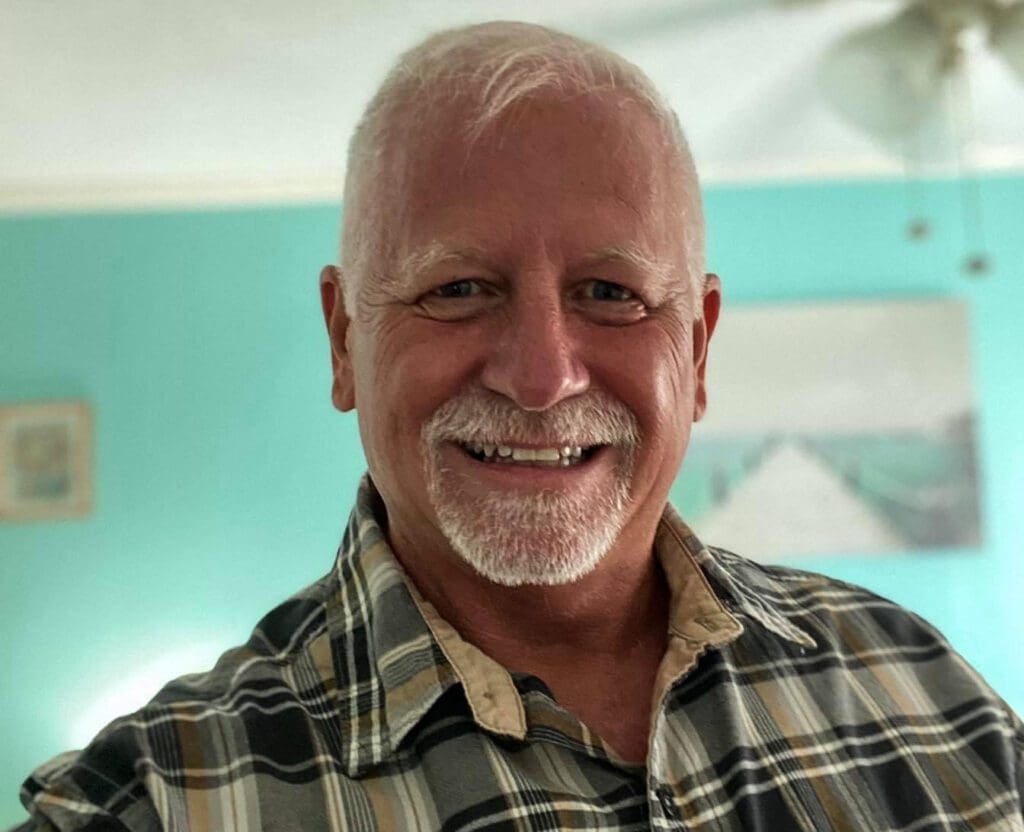 A smiling man wearing a plaid shirt.