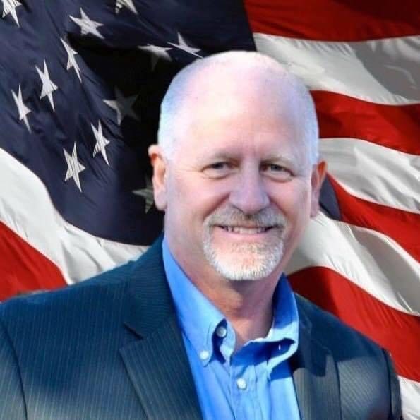 A man standing in front of the American Flag.