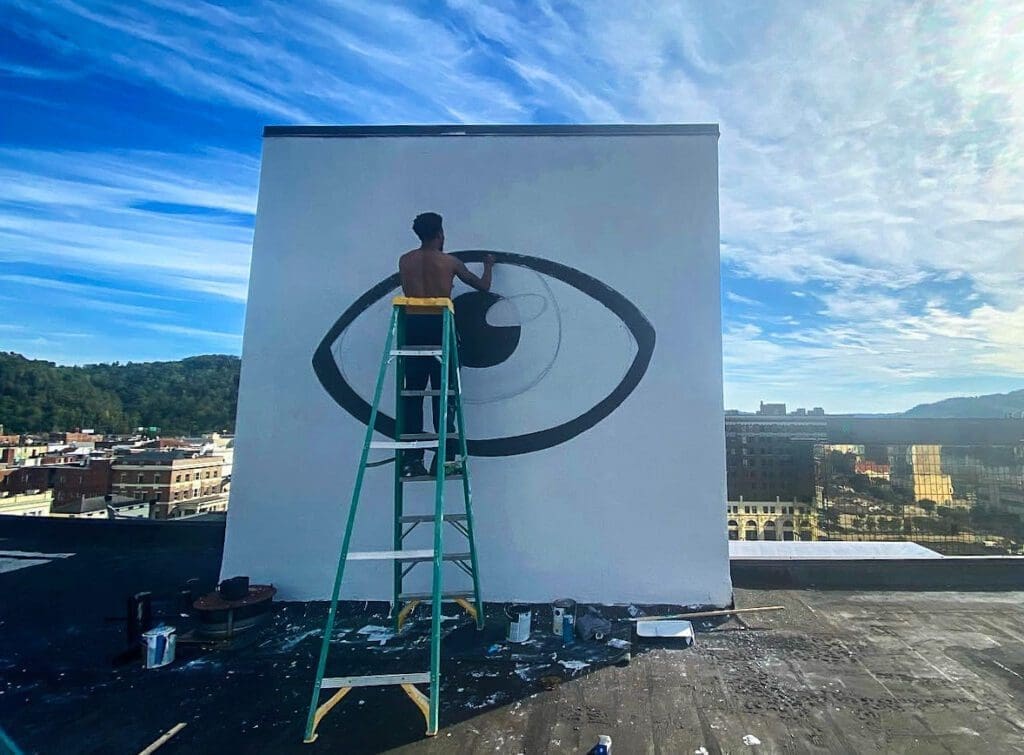 A man on a ladder painting.