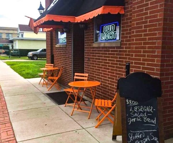 A bar with orange tables outside.