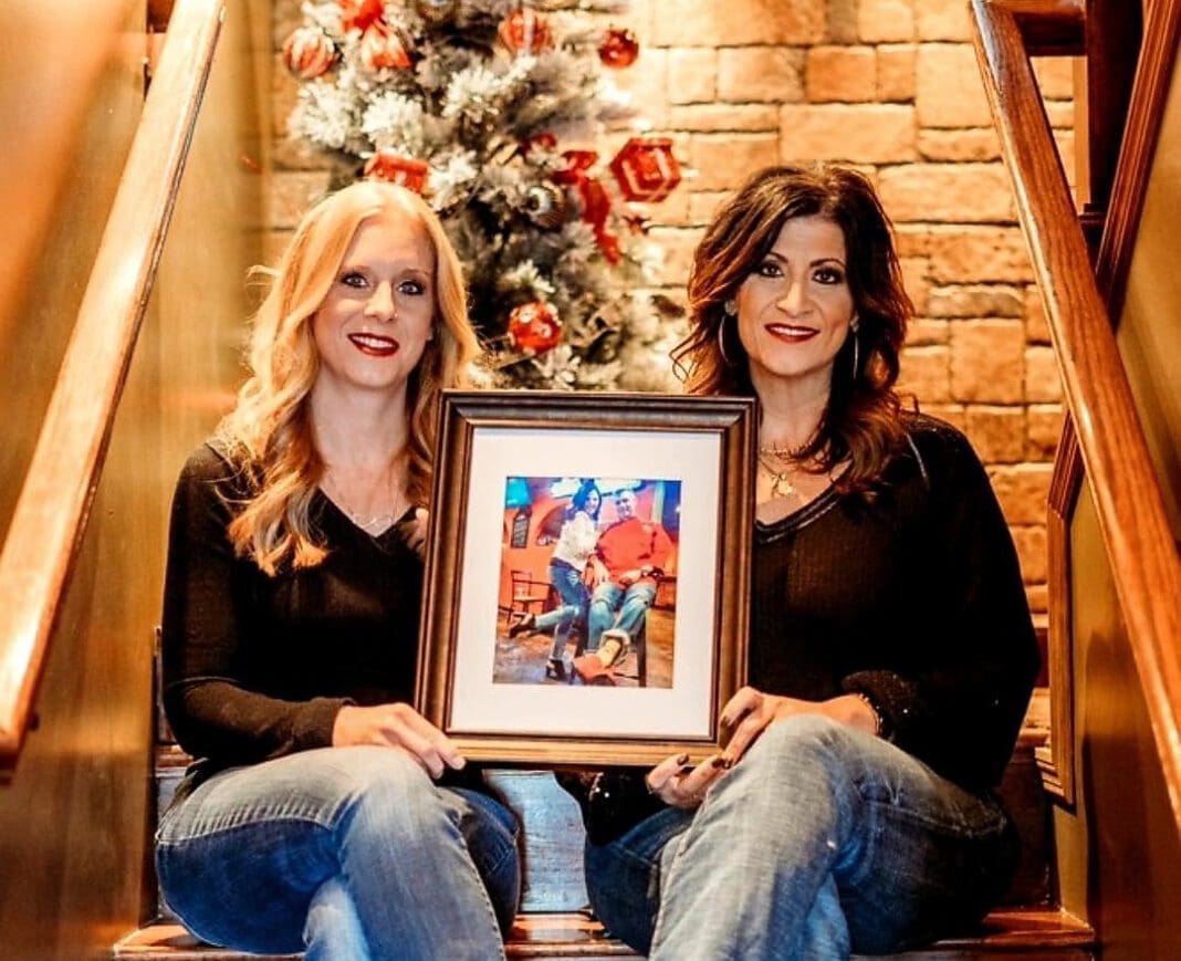 Two woman holding a portrait.