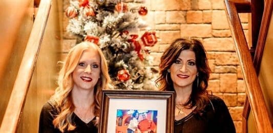 Two woman holding a portrait.