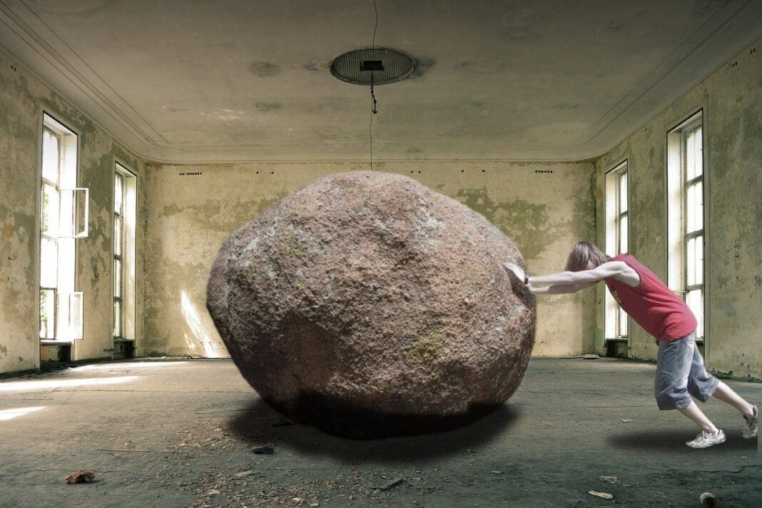 A person pushing a large rock.