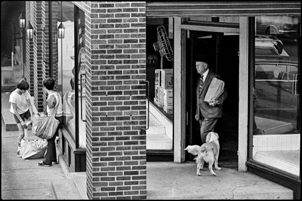 An old guy coming out of a liquor store with booze.