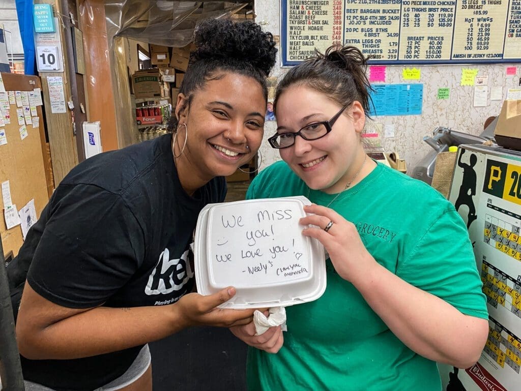 Two girls holding a box of food.