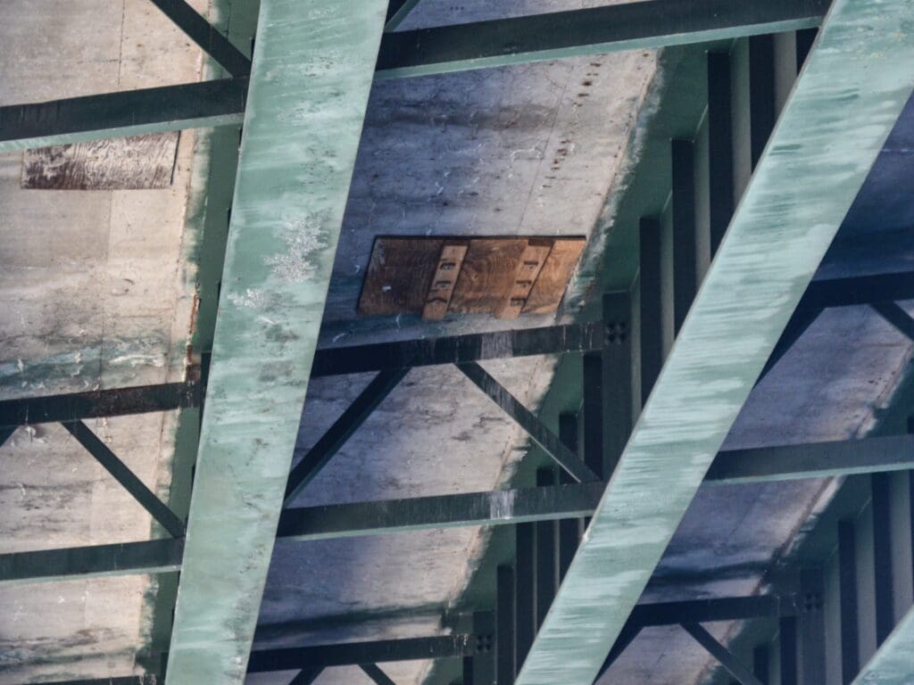 A piee of wood under a bridge.