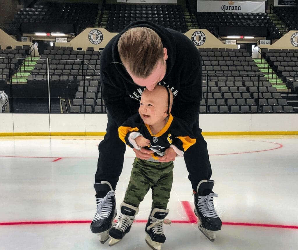 A father with his son on the ice.