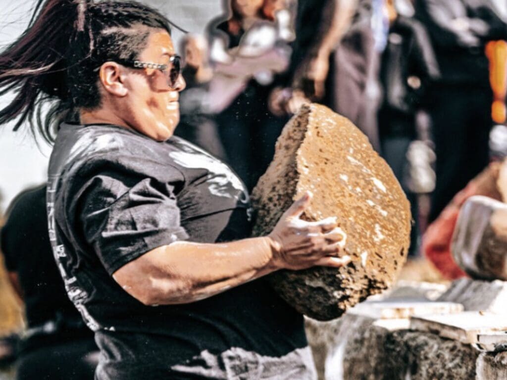 A woman carrying a big rock.