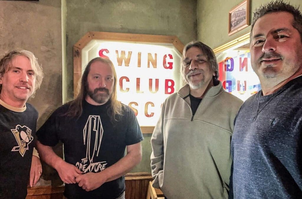 Guys in front of a sign.