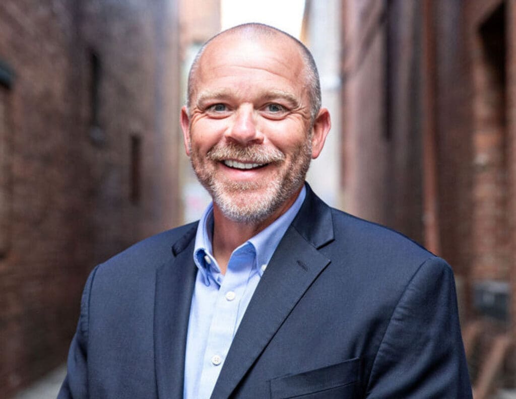 A smiling man in an alley.