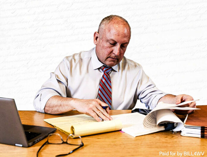 He is sitting at a desk.